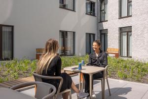 two women sitting at a table in front of a building at Citybox Antwerp in Antwerp