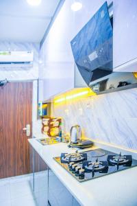 a kitchen with a sink and a stove top oven at Plistbooking Xive 3 bedroom Luxury Abuja Apartment in Abuja