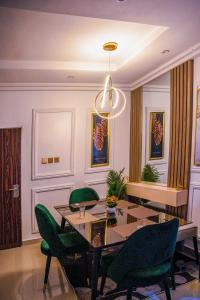 a dining room with a table and green chairs at Plistbooking Xive 3 bedroom Luxury Abuja Apartment in Abuja