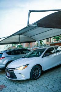 a white car parked under a canopy in a parking lot at Plistbooking Xive 3 bedroom Luxury Abuja Apartment in Abuja