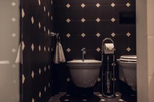 a bathroom with a toilet and a black and white tiled wall at Loom in Bolzano