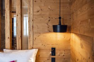 a bedroom with a wooden wall with a pendant light at Loom in Bolzano