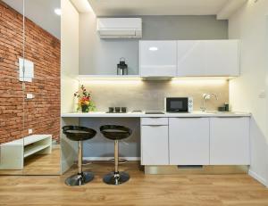 a kitchen with white cabinets and two bar stools at Bed of Roses APT 1, Luxury, Designer decorated in Zagreb