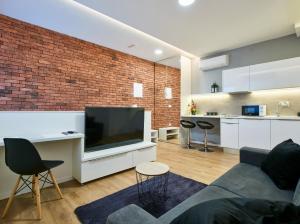 a living room with a tv and a brick wall at Bed of Roses APT 1, Luxury, Designer decorated in Zagreb