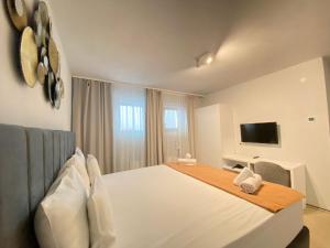 a bedroom with a large white bed and a television at CoolKush Boutique in Constanţa