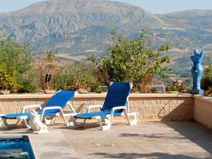 Tres sillas azules sentadas en un patio con montañas al fondo en Casa Oasis, en Álora