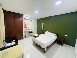 - une chambre avec un lit blanc et un mur vert dans l'établissement Calaveritas Rooms, à Playa del Carmen