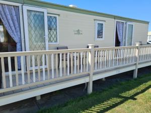 a mobile home with a wooden porch and fence at Corner pitch 4 berth caravan in Ingoldmells