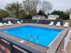 a large swimming pool with chairs and a blue poolvisor at Static Caravan KL13 in Bettws-Evan