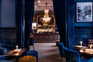 bar z niebieskimi ścianami i stołami oraz żyrandolem w obiekcie Varbergs Stadshotell & Asia Spa w mieście Varberg