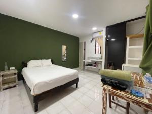 een slaapkamer met een bed en een groene muur bij Calaveritas Rooms in Playa del Carmen