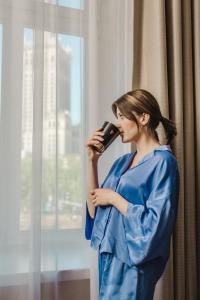 a woman in a blue dress talking on a cell phone at Hotel Polonia Palace in Warsaw
