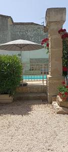 une terrasse avec un parasol et une piscine dans l'établissement Lacanepière, à Générac