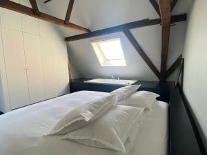 una camera da letto con un letto con cuscini bianchi e una finestra di ANNA a Gand