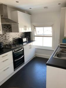 a kitchen with white cabinets and a stove top oven at The View Apartments Castle Road in Scarborough