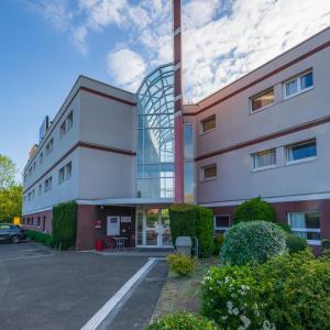 un bâtiment avec une voiture garée sur un parking dans l'établissement Hôtel Cerise Auxerre, à Monéteau