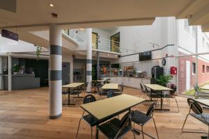 une cafétéria avec des tables et des chaises dans un bâtiment dans l'établissement Hôtel Cerise Auxerre, à Monéteau