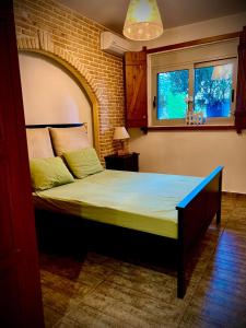 1 dormitorio con 1 cama grande en una pared de ladrillo en Ένας ευχάριστος χώρος με πισίνα, en Porto Rafti