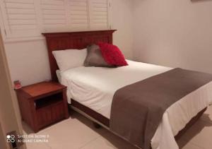 a bedroom with a bed with a red pillow on it at Beacon Rock - 6 sleeper Luxurious Apartment in Durban