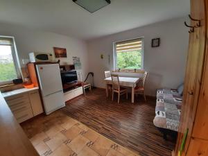 a kitchen and dining room with a table and a refrigerator at domek Drewniany na wiejskiej in Lubiatowo