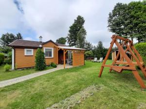a tiny house with a swing in the yard at Domek Drewniany 2 in Lubiatowo