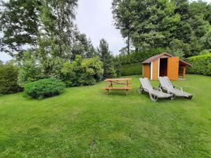 a yard with two chairs and a table and a cabin at Domek Drewniany 2 in Lubiatowo