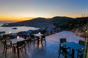 un restaurant avec des tables et des chaises et une vue sur la ville dans l'établissement Sky Way SKK Luxury Apartments, à Saranda