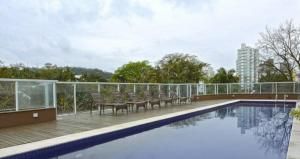a balcony with chairs and a swimming pool on a building at Loft no coração da cidade de Blumenau in Blumenau