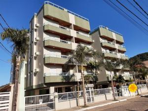 ein hohes Gebäude mit Palmen davor in der Unterkunft Conforto, 2 vagas garag lazer a poucos passos do mar! Apto 306/B, Ana Luiza - Praia Grande in Ubatuba