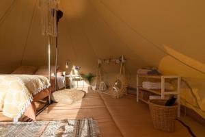 Glamping La Mimosa CONIL في كونيل دي لا فرونتيرا: غرفة نوم مع خيمة مع سرير وطاولة