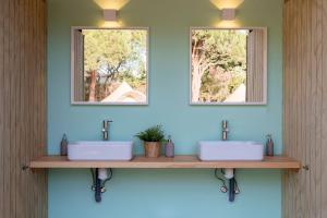 two sinks in a bathroom with two mirrors at Glamping La Mimosa CONIL in Conil de la Frontera