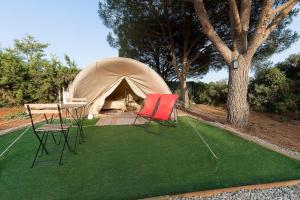 a tent with two chairs and a table in front of it at Glamping La Mimosa CONIL in Conil de la Frontera
