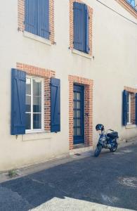 uma moto estacionada em frente a um edifício com persianas azuis em La Maison Bleue em Villefranche-Sur-Cher