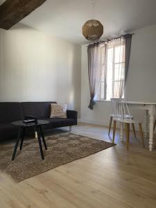 uma sala de estar com um sofá, uma mesa e cadeiras em La Maison Bleue em Villefranche-Sur-Cher
