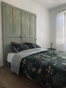um quarto com uma cama com uma cabeceira verde em La Maison Bleue em Villefranche-Sur-Cher