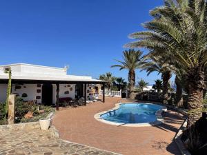 a swimming pool in front of a house with palm trees at Casa Palmeral in Mácher