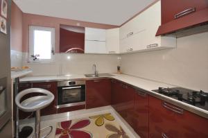 una cocina con armarios rojos y blancos y fregadero en Apartments by the sea Arbanija, Ciovo - 11592 en Trogir