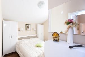 um quarto branco com uma cama e um espelho em House Glasnović em Cavtat