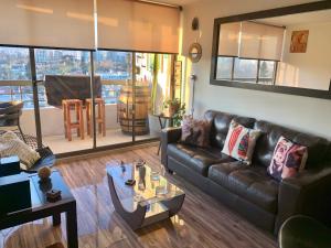 uma sala de estar com um sofá de couro e uma mesa em Descanso y Tranquilidad em Santiago