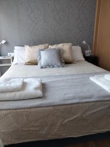 ein großes Bett mit weißer Bettwäsche und Kissen darauf in der Unterkunft APARTAMENTO BEATRIZ in Pobra do Caramiñal