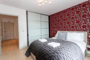 ein Schlafzimmer mit einem großen Bett mit einer roten Wand in der Unterkunft Iconic Luxury Manchester Apartment in Manchester