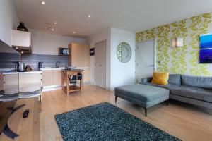 Una sala de estar con un sofá y una cocina. en Iconic Luxury Manchester Apartment, en Mánchester