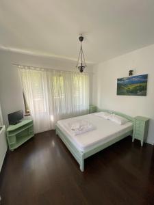a white bedroom with a bed and a tv at Pensiunea Sandra in Bran