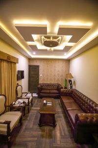 a living room with a leather couch and chairs at Jhelum Inn Hotel in Jhelum