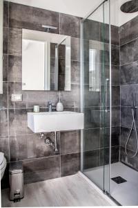 a bathroom with a sink and a glass shower at Oliveto Bed and Breakfast in Alghero