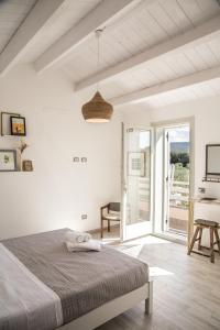 a white bedroom with a bed and a balcony at Oliveto Bed and Breakfast in Alghero