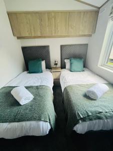 two beds in a room with green and white at Fir Tree Lodge with Hot Tub in York