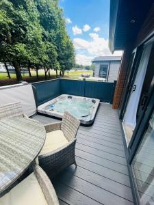 a deck with a table and chairs and a hot tub at Fir Tree Lodge with Hot Tub in York