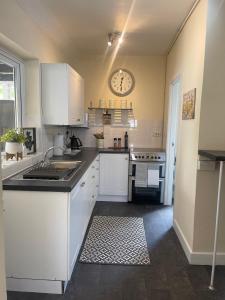 a kitchen with white cabinets and a clock on the wall at Delightful 2 bed detached home with secure parking in Huntington
