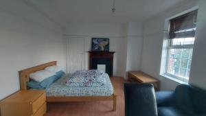 um quarto com uma cama, uma cadeira e uma janela em London Edgware Station Apartment em Londres